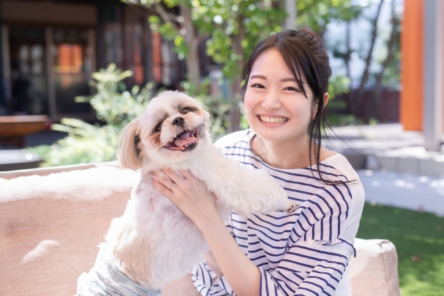 犬と笑い合う女性の写真